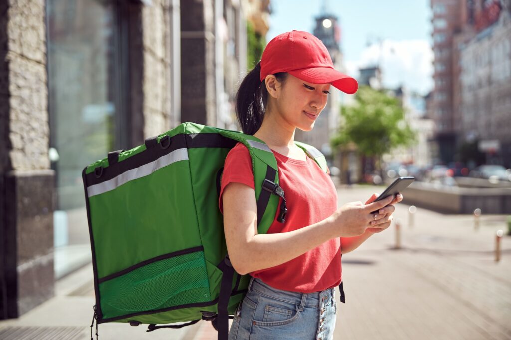 Asian student delivering food through city using mobile phone