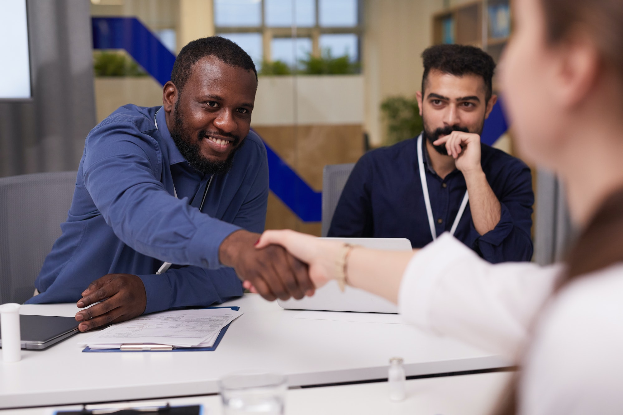 Happy young African-American businessman shaking hand of female doctor